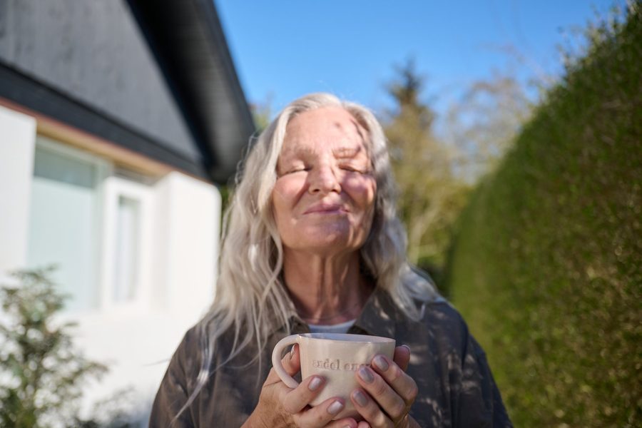 Kvinde med kaffekop i morgensolen