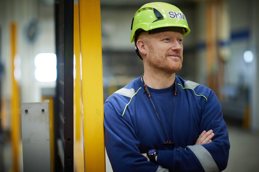 Smilende medarbejder med hjelm i produktionen