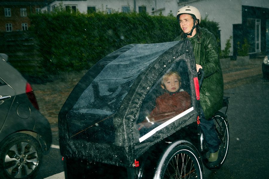 Mor på ladcykel med barn i regnvejr