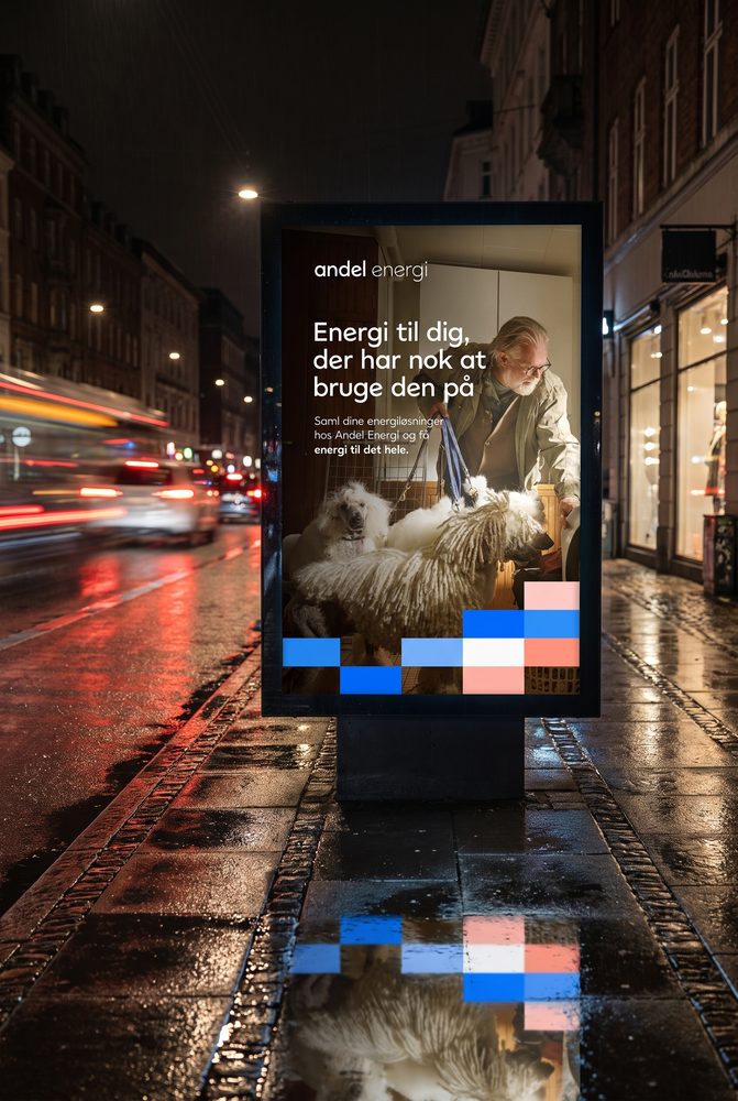 Bagbelyst lyskasse med Andel Energi-plakaten på en regnvåd københavnsk gade om natten